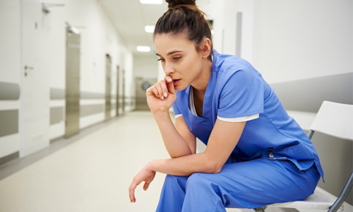 Concerned and stressed nurse sits in quiet corridor during a shift